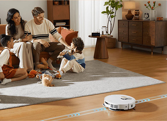 家族が座るわきを床の木目にあわせて走っていくロボット掃除機